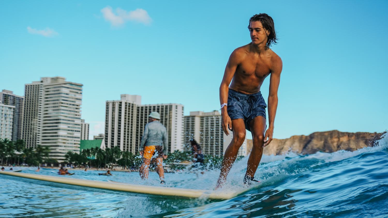 Man surfing off Waikiki with hotel towers behind