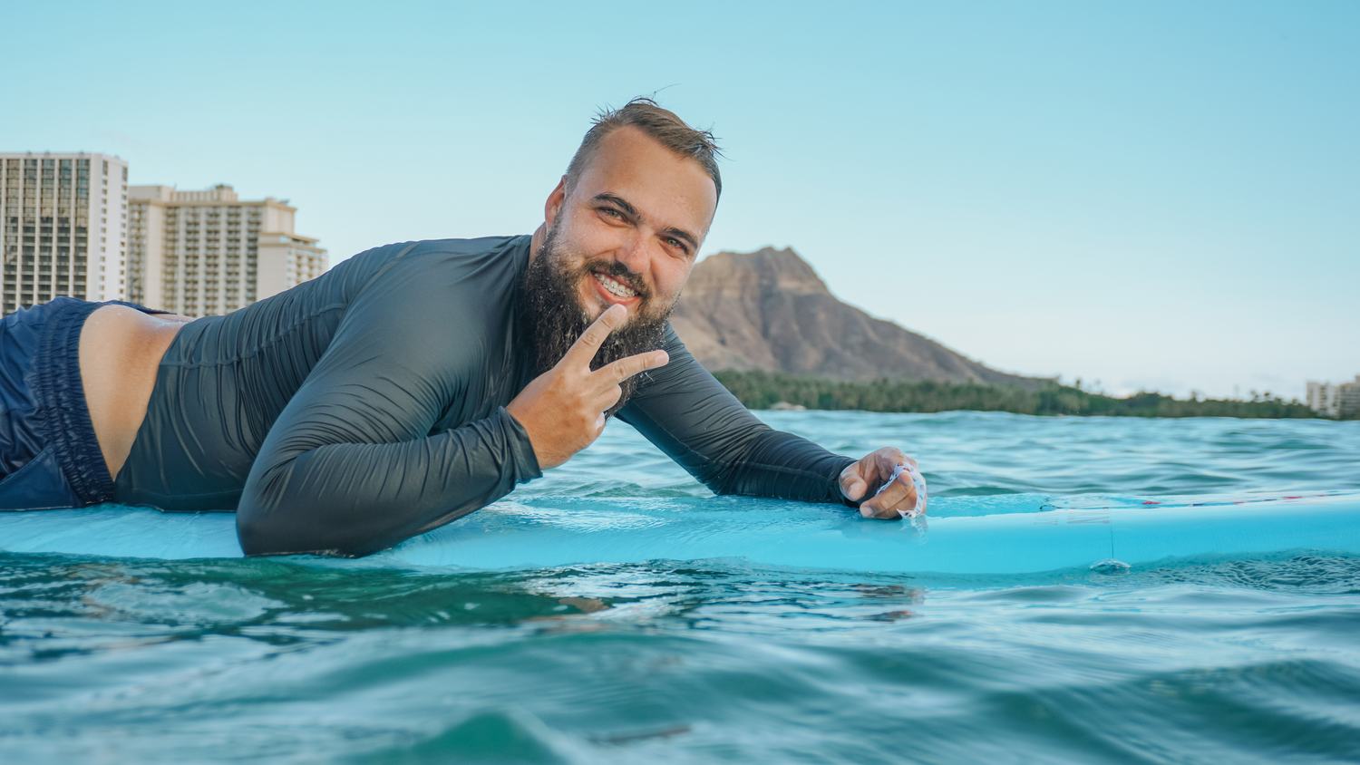 Man giving a peace sign while lying on a paddleboard