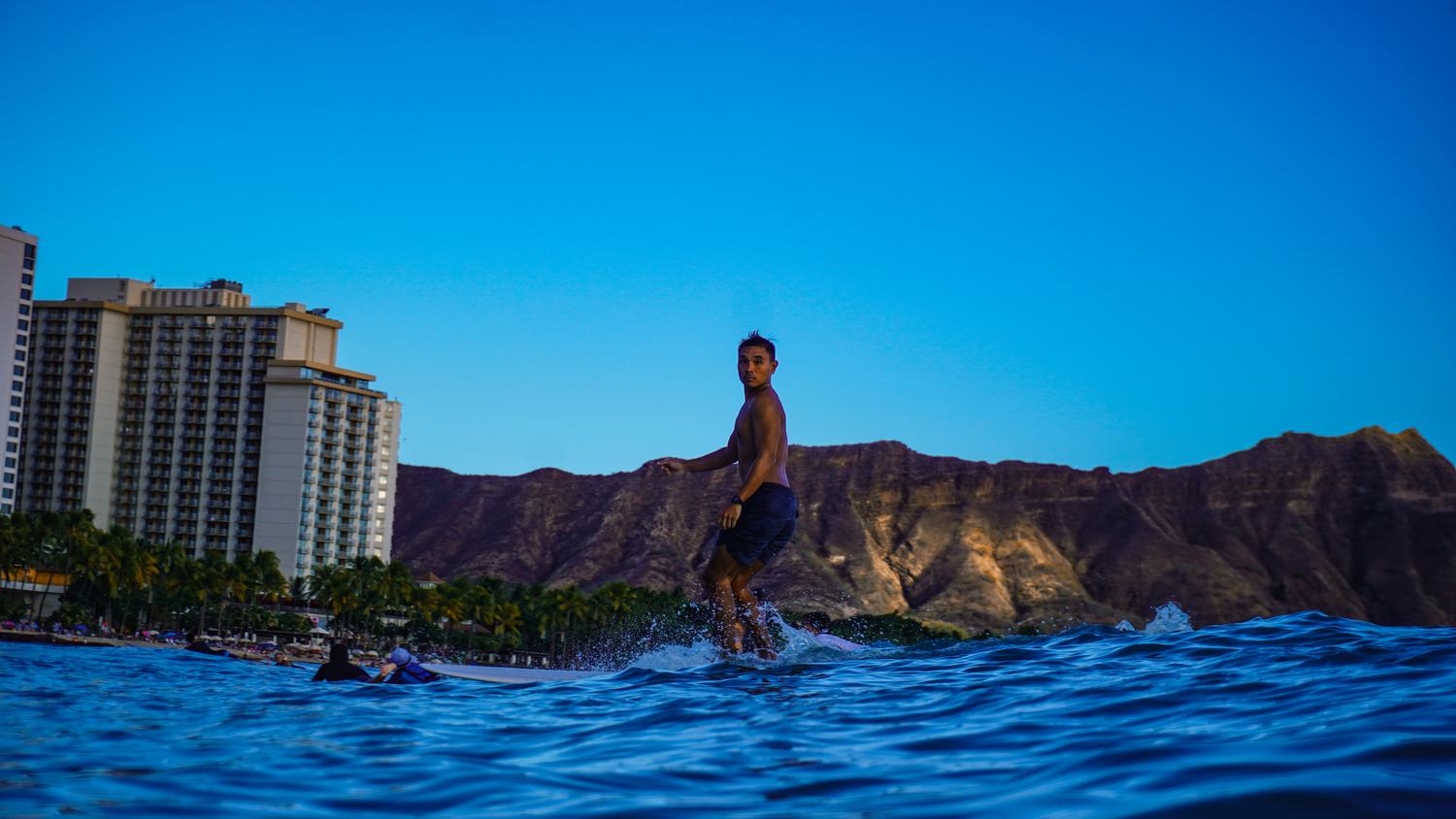 Man surfing, glancing back at the camera at dusk