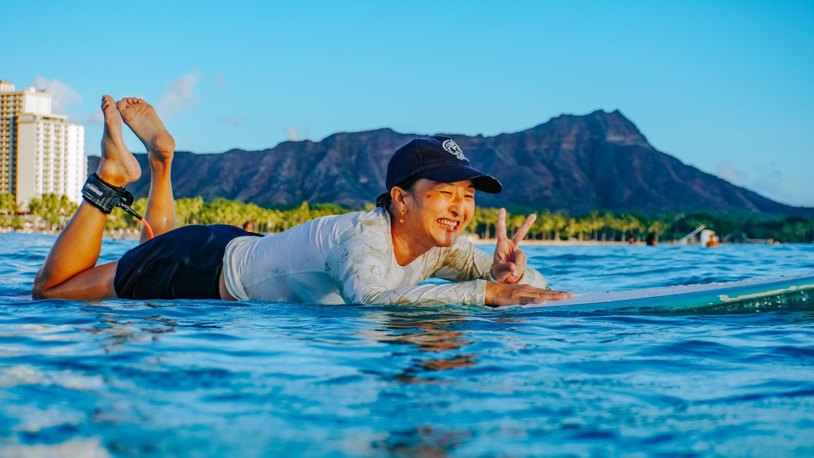 Woman surfing at sunset with Diamond Head behind