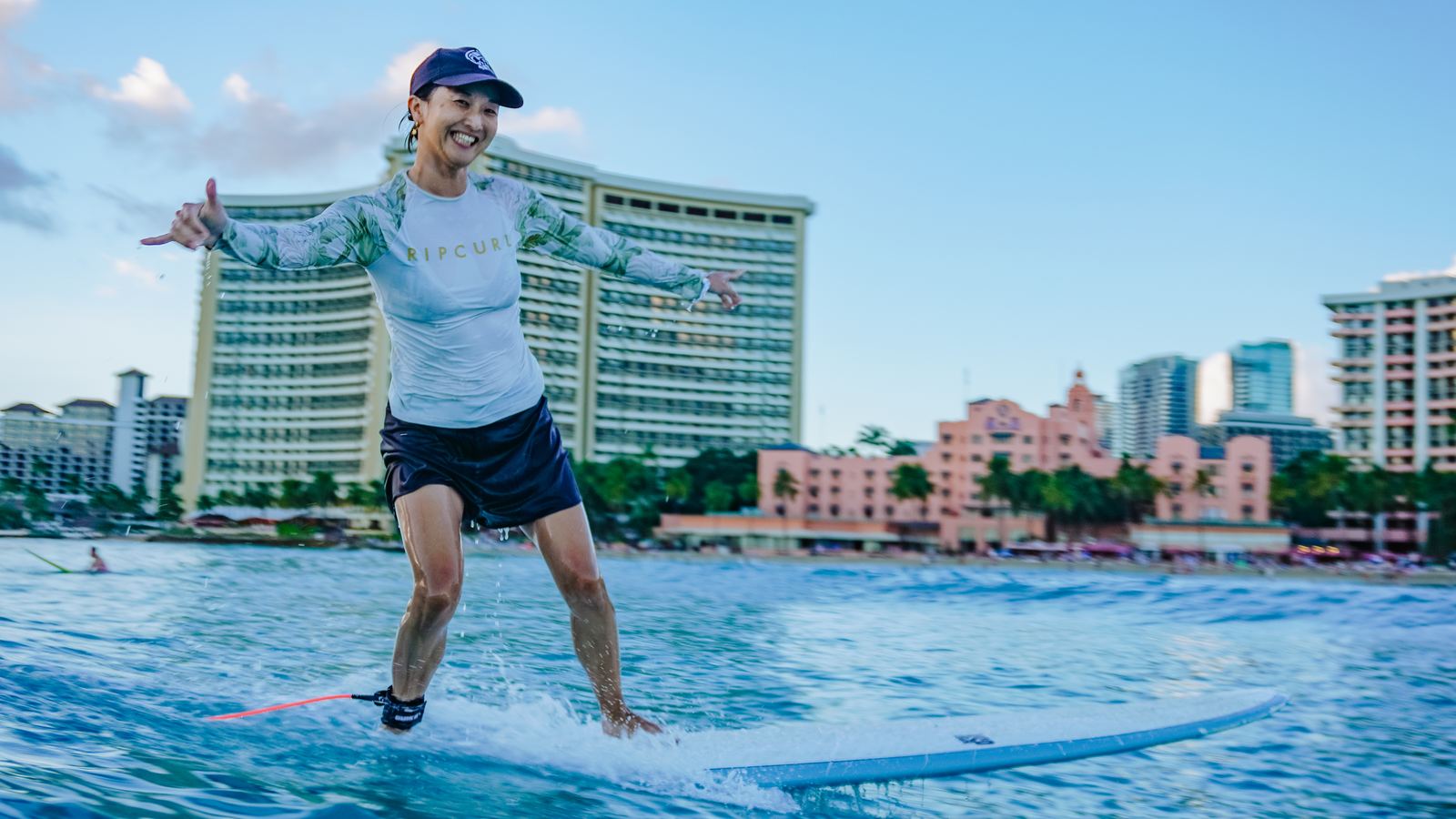 Woman sitting on surfboard with Diamond Head behind
