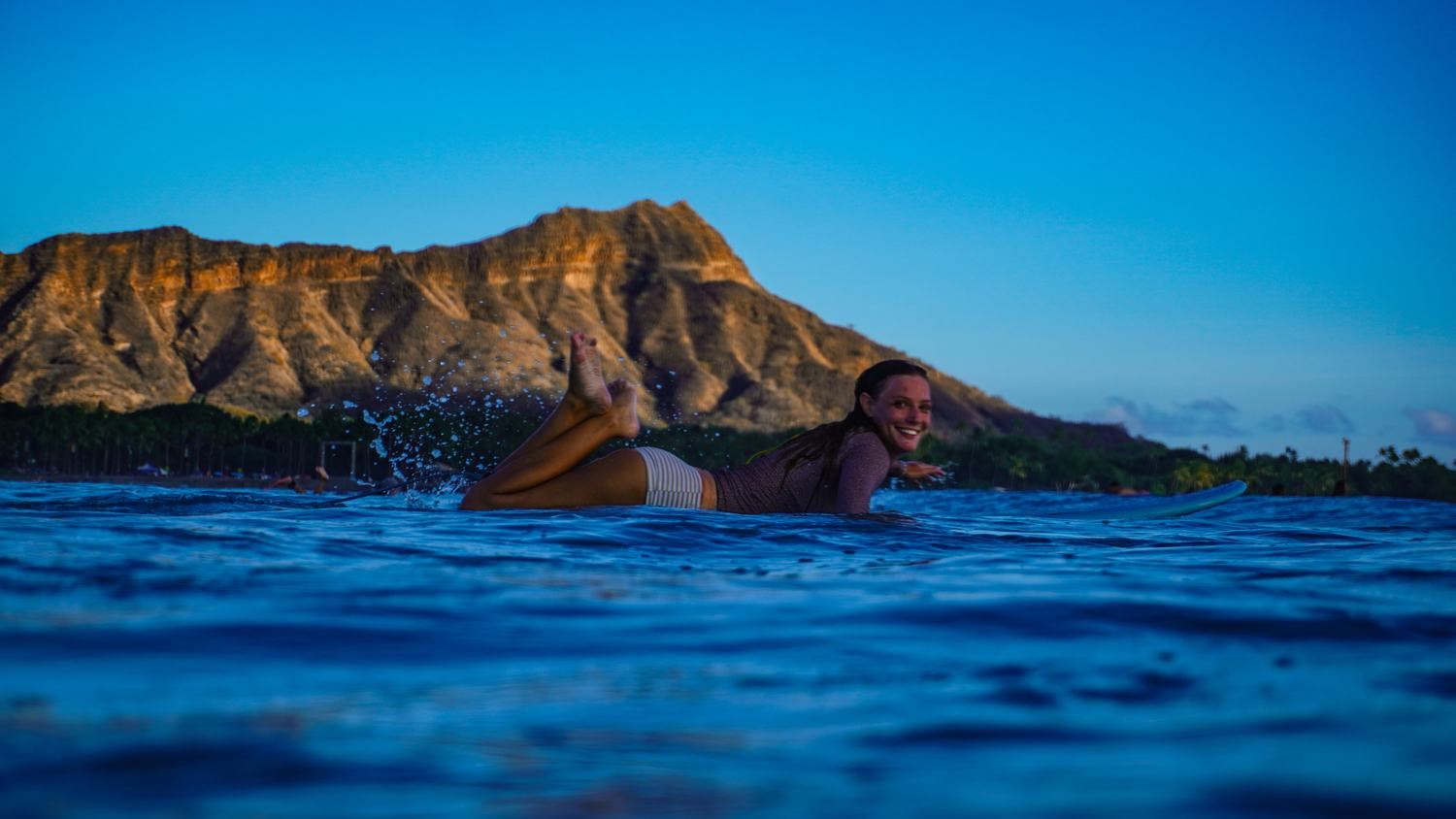 Woman lying on surfboard, laughing