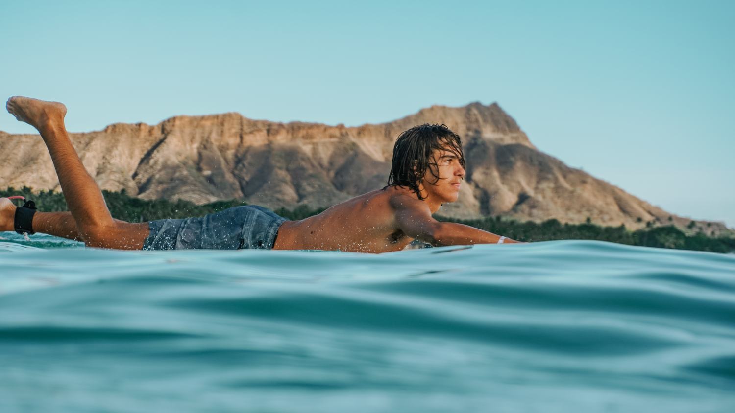 Man lying prone on a paddleboard with foot raised