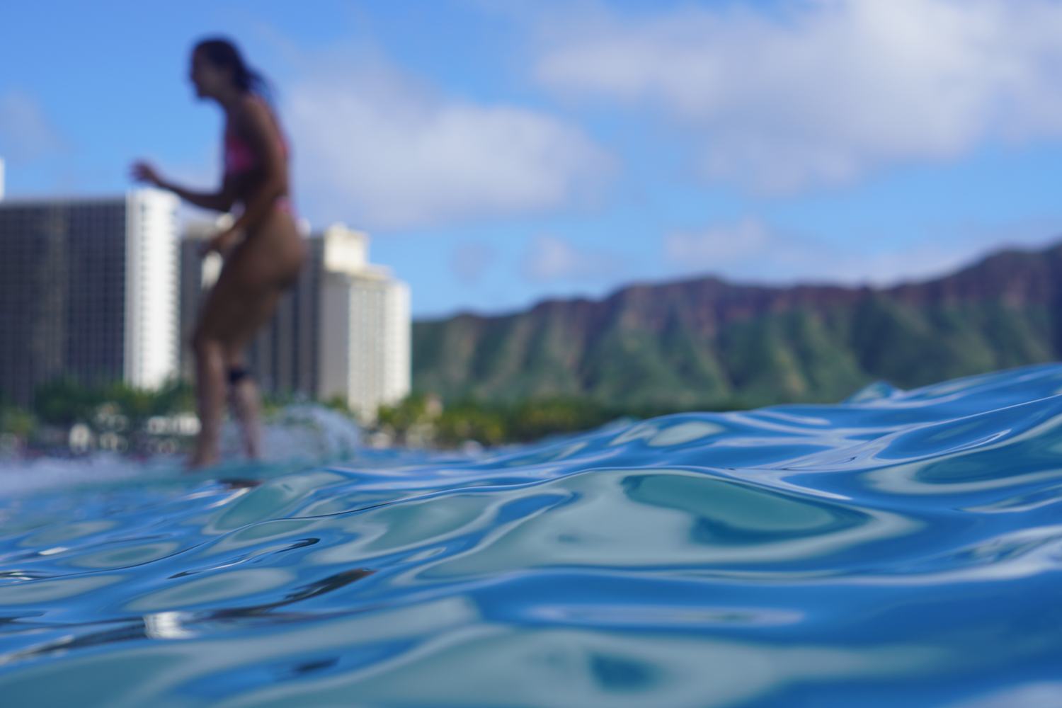 Woman standing in the surf, soft focus, Waikiki skyline behind