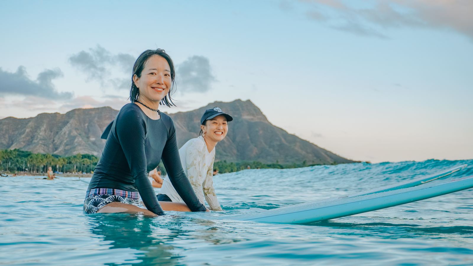 Two women sitting on a paddleboard laughing
