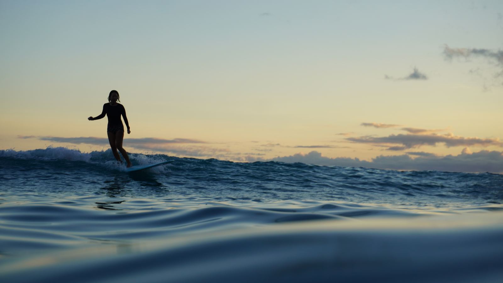 Woman surfing at sunset